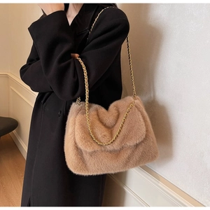 Detail of light brown faux fur tote bag with a gold metal and leather chain strap