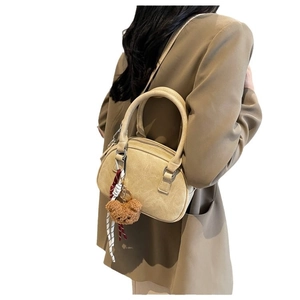 Minimalist beige crossbody bag with plush bear charm and textured leather straps