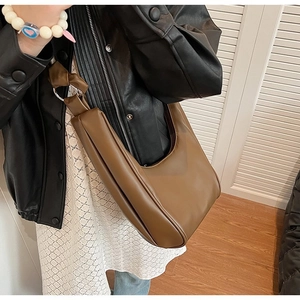Detail of coffee brown dumpling bag featuring knotted handle and matte faux leather texture