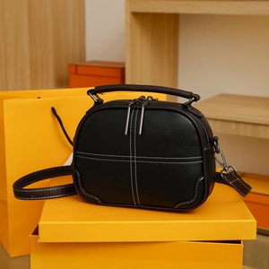 Macro detail of black litchi grain leather bag with white contrast stitching accents