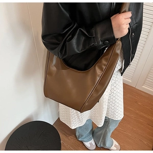Brown semi-moon hobo bag with stitching detail shown worn by a model in a minimalist setting