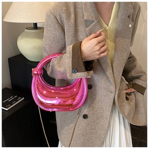 Détail d'un sac demi-lune rose métallisé avec poignée nouée et chaîne dorée