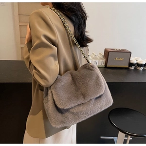Detail of grey faux fur shoulder bag with gold chain strap on a stylish lifestyle setting