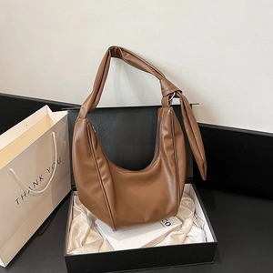 Detail of a brown PU leather crescent bag with knot strap in a premium gift box