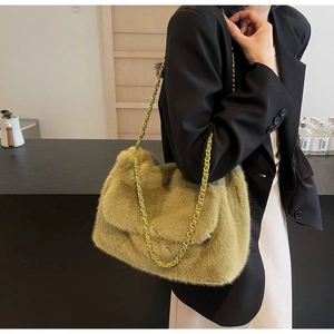 Detail of green faux fur shoulder bag with woven gold chain strap on a black blazer