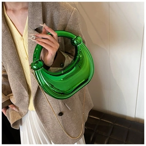Détail d'un sac de soirée vert brillant avec chaîne dorée et poignée ronde