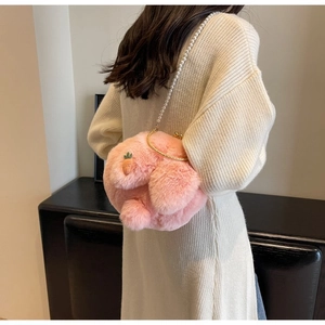 Détail d'un sac lapin en peluche rose avec poignée dorée et bandoulière en perles