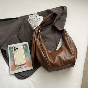 Detailed view of dark brown faux leather hobo bag with knotted strap and pleats