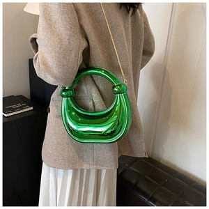 Gros plan du sac à main vert métallisé avec chaîne dorée porté par le mannequin
