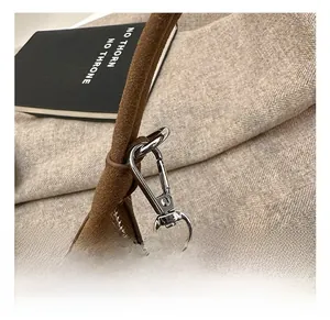 Détail des crochets en métal argenté et de la chaîne sur un sac en daim marron
