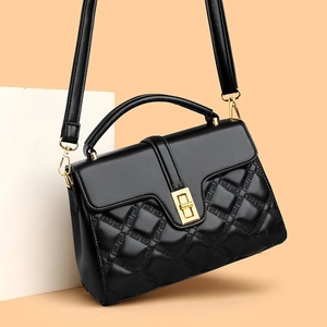 Quilted black crossbody bag with gold lock and chain strap on geometric background