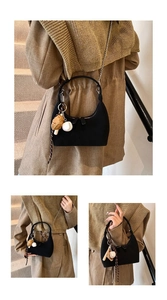 Détail d'un sac sous le bras noir avec breloques de baseball et chaîne argentée