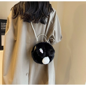 Détail d'un sac noir en peluche avec bandoulière perle et écusson carotte sur mannequin