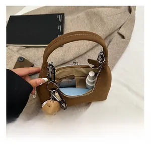 Capacité interne du sac à bandoulière en daim marron contenant crème solaire et rouge à lèvres