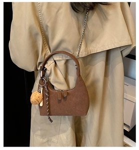 Détail du sac demi-lune en daim marron avec chaîne argentée et breloque gant de baseball