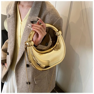 Détail d'un sac de soirée croissant doré avec poignée à nœud métallique et bandoulière