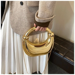 Détail d'un sac demi-lune en métal doré avec poignée épaisse et bandoulière chaîne
