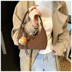 Sac à bandoulière marron en forme de croissant avec charm champignon porté par mannequin