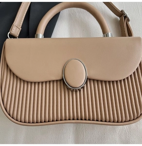 Detail of beige pleated handbag with silver oval twist lock and smooth leather top flap