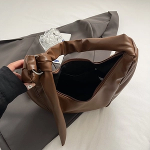 Brown PU leather crescent bag with top knot handle and silver rings in flat lay view