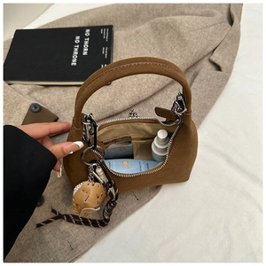 Gros plan de l'intérieur d'un sac en daim marron avec cosmétiques et breloque gant