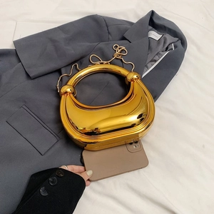Sac de soirée doré chic avec finition métallique et chaîne à côté d'un smartphone