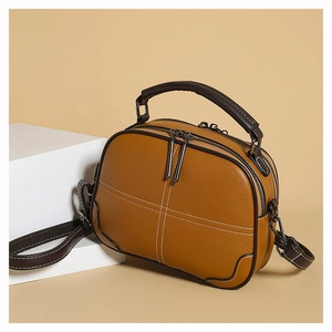 Retro brown leather crossbody bag with white stitching and top handle in studio lighting