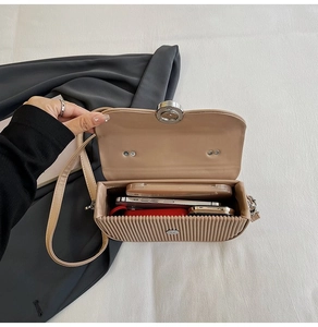 Interior view of beige pleated crossbody bag showing storage capacity for phone and cosmetics