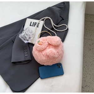 Détail d'un sac rond en peluche rose avec breloque carotte et bandoulière perlée