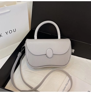 Detailed macro of pleated light gray handbag with silver buckle and detachable strap