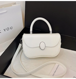 Close-up of white pleated tote bag with silver oval buckle inside a black gift box