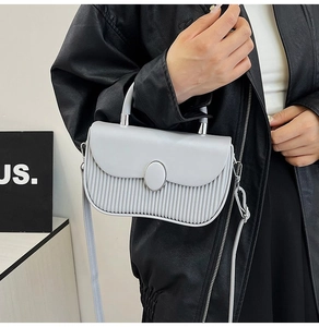 Close-up of light gray handbag featuring vertical pleated texture and curved handle