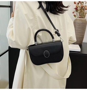 Detailed back view of black pleated handbag with oval silver buckle and adjustable strap
