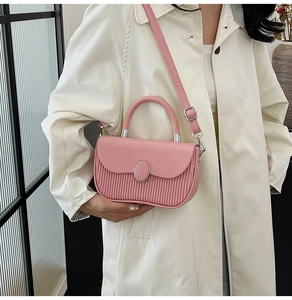 Close-up of pink shoulder bag featuring pleated texture and silver metal buckle detail