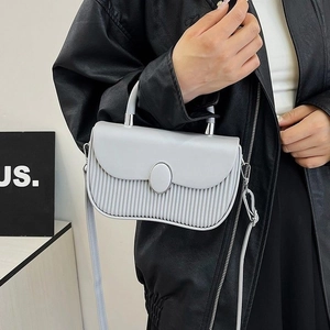 Detail of light gray crossbody bag showing pleated texture and silver oval buckle