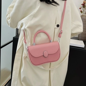Pink pleated crossbody handbag with oval buckle and silver handle shown on model
