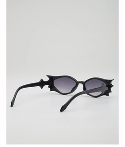 Macro detail of gothic bat-shaped sunglasses with black frame and purple gradient lenses