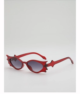 Detail of red flame bat-shaped sunglasses with translucent frames for party outfits