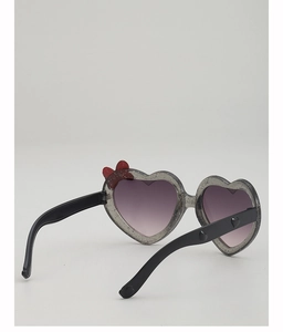 Détail de lunettes de soleil cœur pailletées avec nœud rouge et verres dégradés