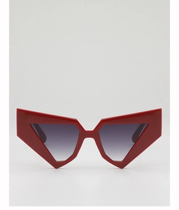 Detail view of bold red geometric cat-eye sunglasses with dark grey gradient lenses