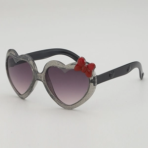 Lunettes de soleil cœur pour enfants avec monture pailletée argent et nœud rouge