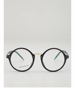 Detail of round black glasses frame featuring gold metal bridge and hinge accents