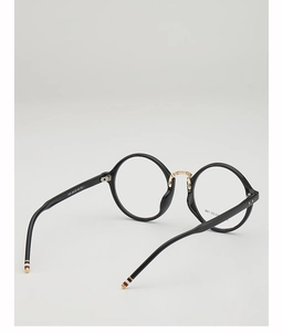 Detail of round black eyewear frame featuring golden bridge and tricolor temple tips