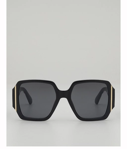 Detailed view of oversized square black sunglasses with luxury vertical gold metal accents