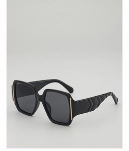 Detail of square oversized black sunglasses featuring textured wide temples and gold accents
