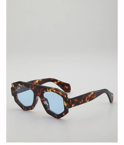 Détail de lunettes de soleil en écaille épaisse avec verres bleu clair sous un angle de côté