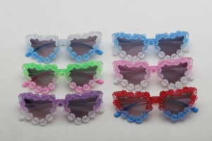 Detail of heart-shaped kids sunglasses with colorful 3D daisy flowers in gradient colors