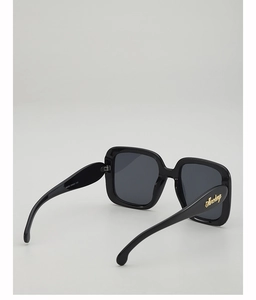 Detail view of black oversized square sunglasses featuring model M2303 and gold logo hinges