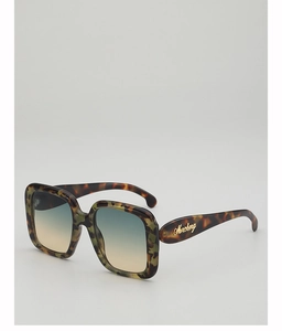 Detail of tortoiseshell frame sunglasses with gradient lenses and gold temple logo
