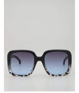 Detailed close-up of oversized square sunglasses with blue gradient lenses and marbled frame